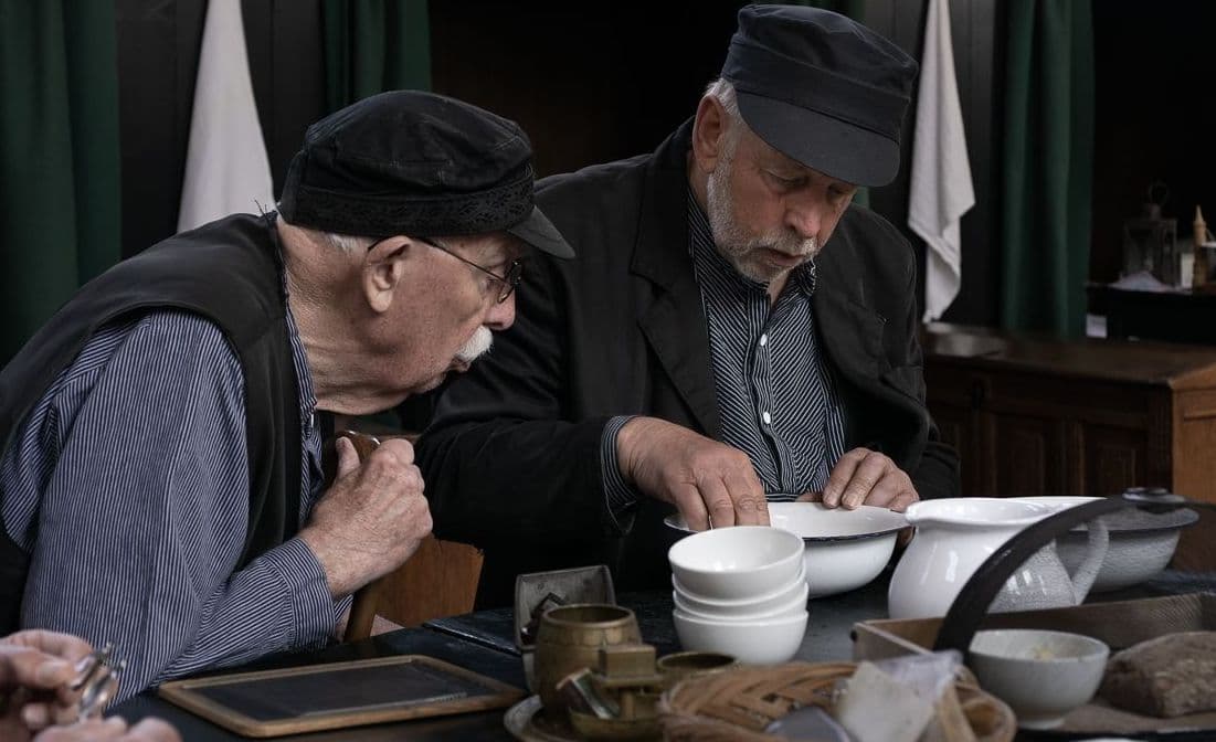 Twee mannen in historische kleding zitten aan een tafel en eten samen in de Mannenzaal, als onderdeel van Levende Historie. Deze foto is gemaakt door: Jolanda van Rijssen